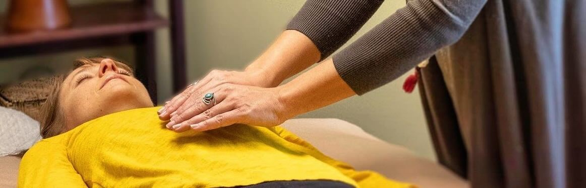 Hands offering Reiki energy healing in a softly lit room